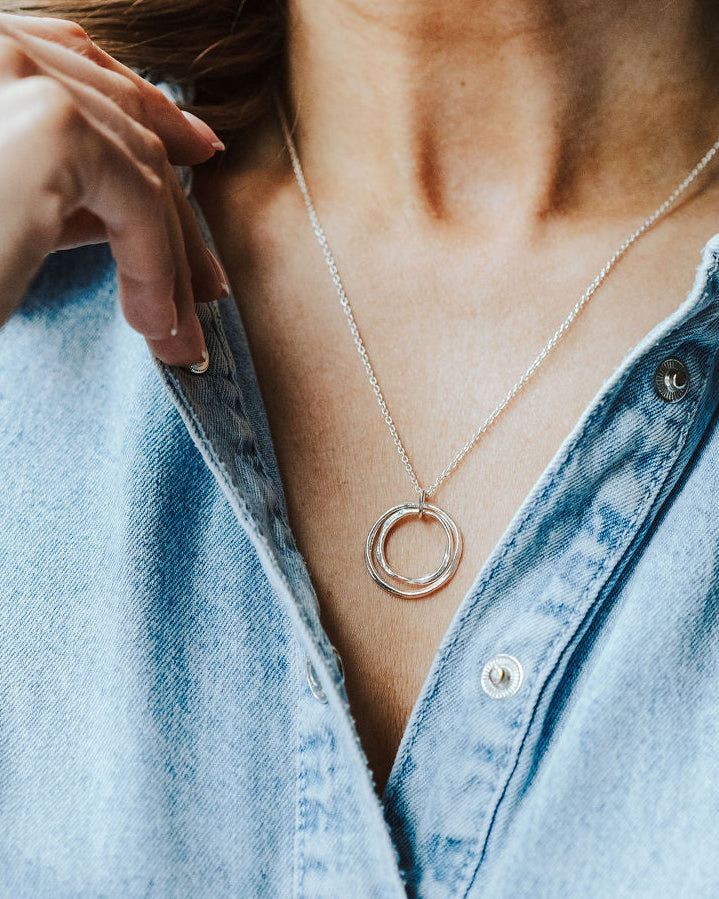 Woman in a denim shirt wearing a silver nested circles necklace