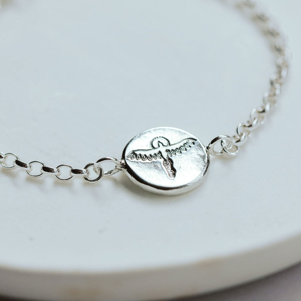 Silver bracelet with a phoenix charm on a white plate