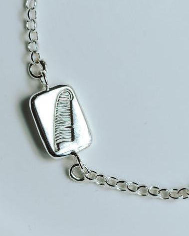 silver feather bracelet on a white dish