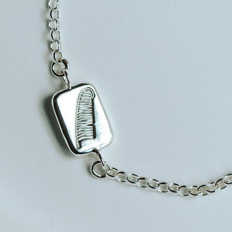 silver feather bracelet on a white dish