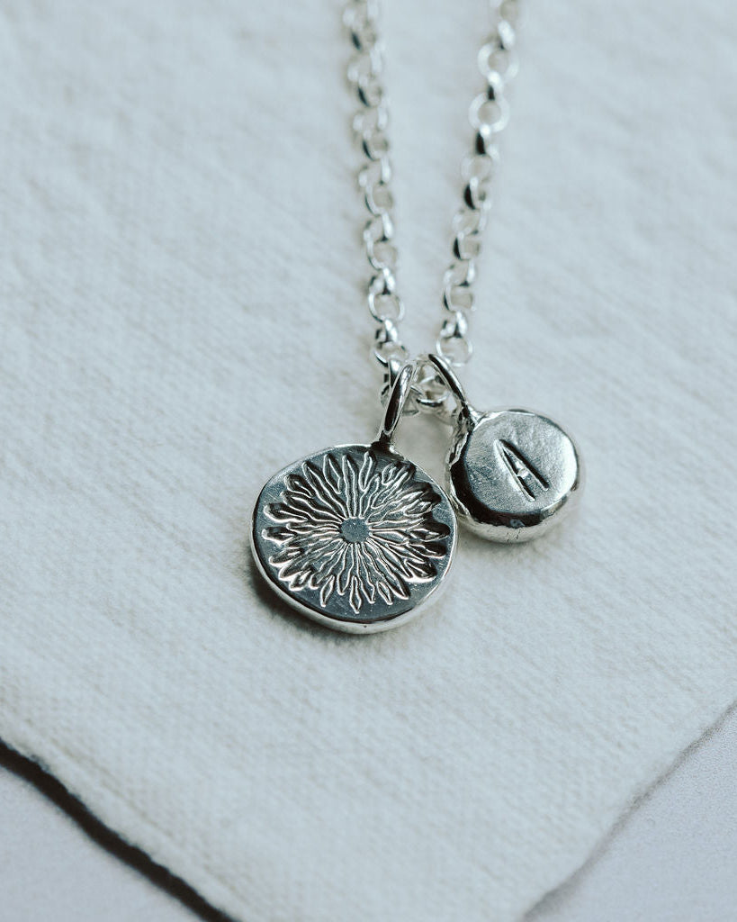 Silver necklace with two pendants on a white background