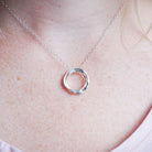 Silver necklace with a interlocking circles pendant on a person wearing a white shirt.