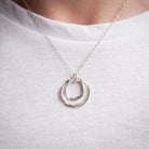 Silver necklace with a double-circle pendant on a white shirt