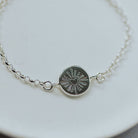 Silver bracelet with a heart design on a white plate