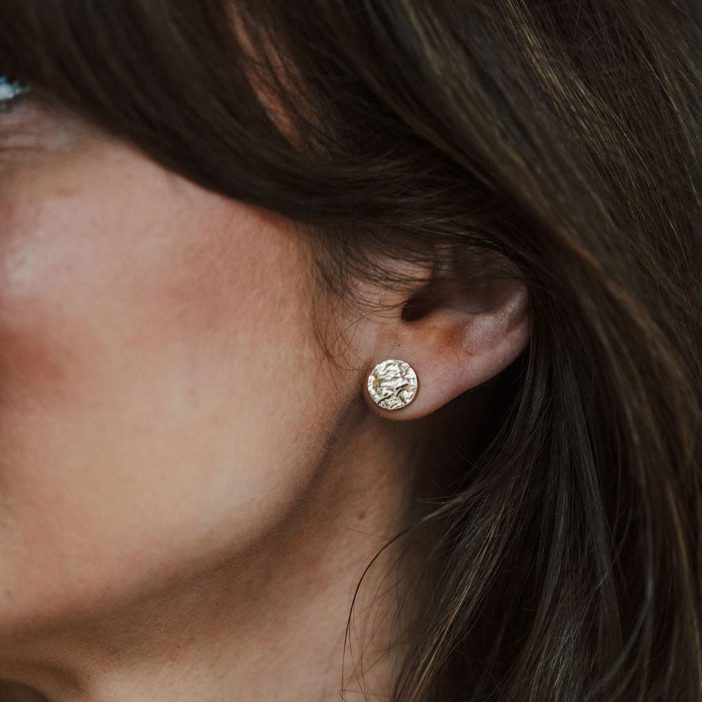 Close-up of an ear wearing a bark textured gold earring.