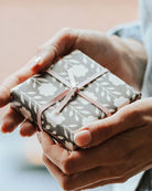 Present wrapped in black and white gift wrap with pink ribbon, held by womans hands