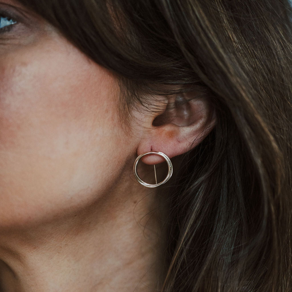 Woman wearing gold circle threader earrings.