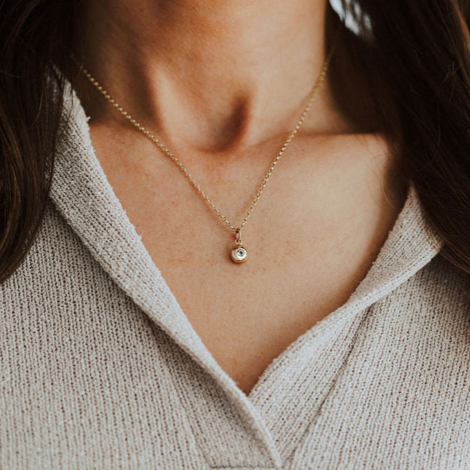 Lady wearing gold pebble pendant set with birthstone.