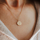 Woman in a beige top wearing a gold phoenix pendant