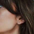 Woman with brown hair wearing 9ct gold tree textured studs.