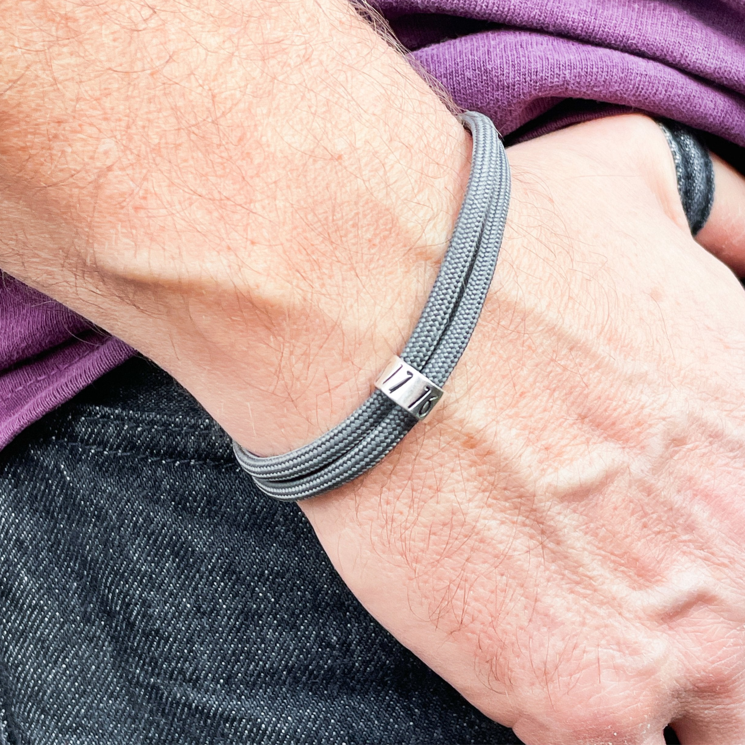 Grey paracord bracelet with silver hand stamped Rune bead. Handmade by Hannah Weston in York.