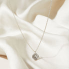 Silver necklace with a tree textured pendant on a white fabric background