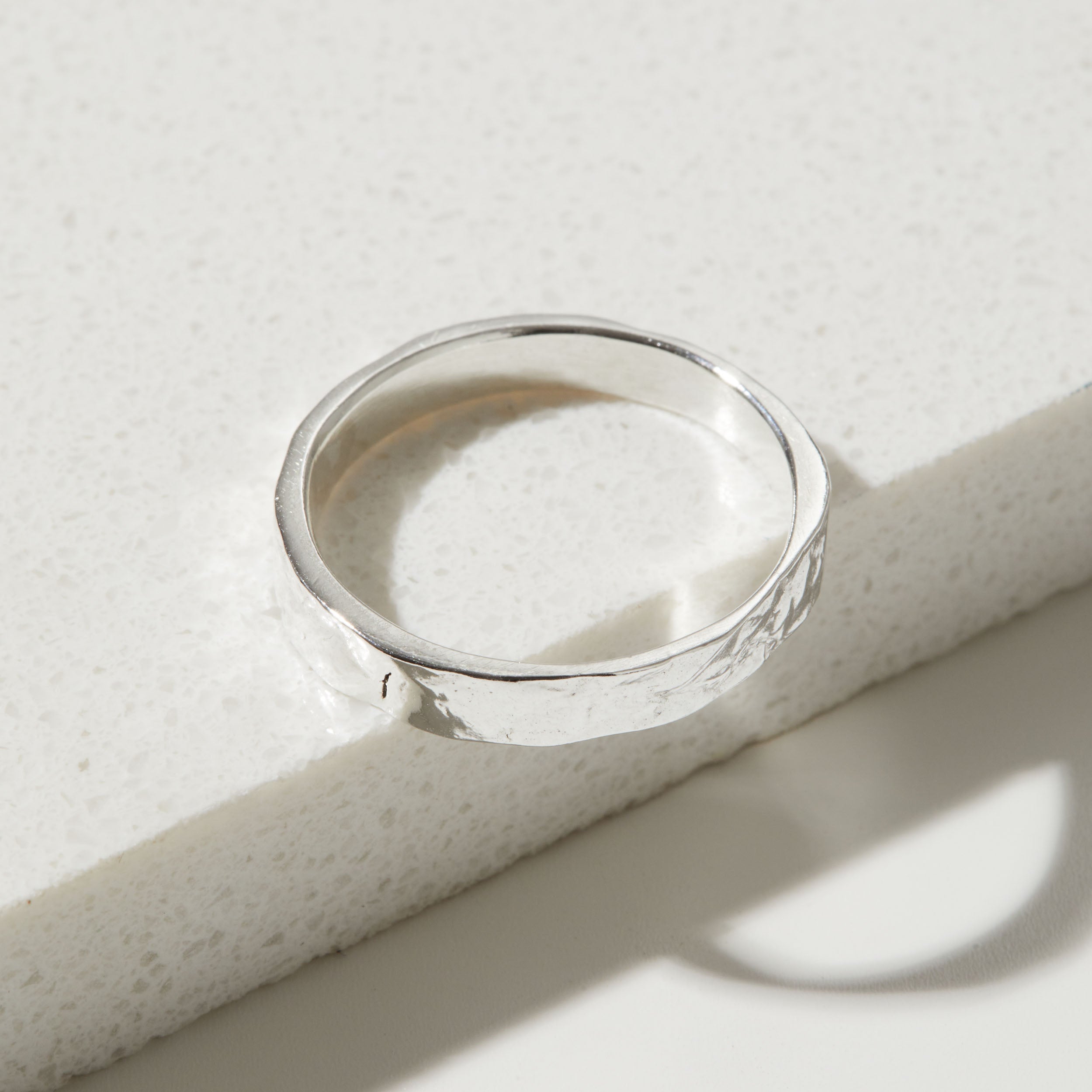 Silver bark textured ring on a textured white surface
