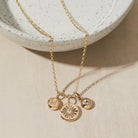 Gold necklace with initial-birthstone-heart charms on a neutral background