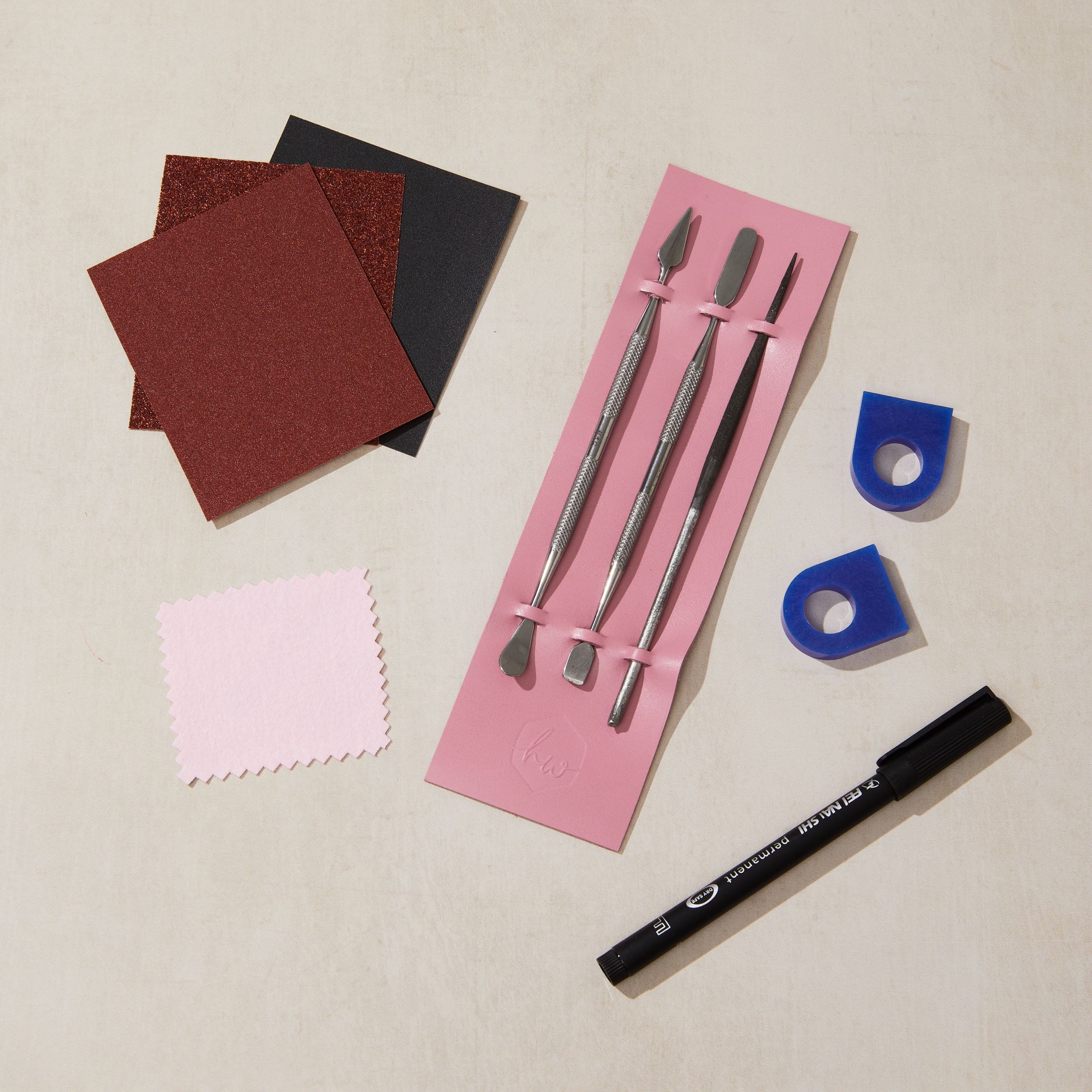 Set of ring carving tools and materials on a beige surface