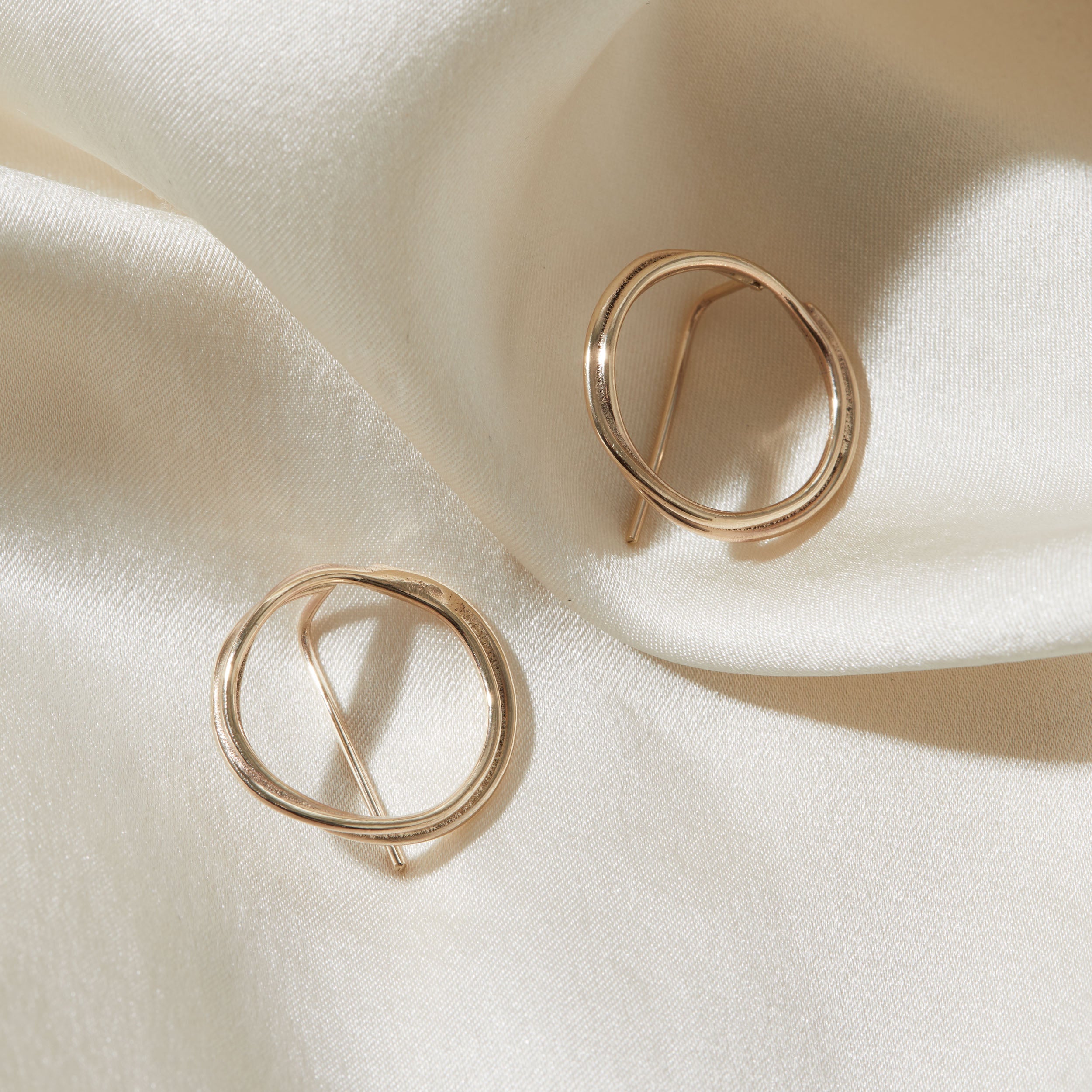 Gold hoop earrings on a beige fabric background
