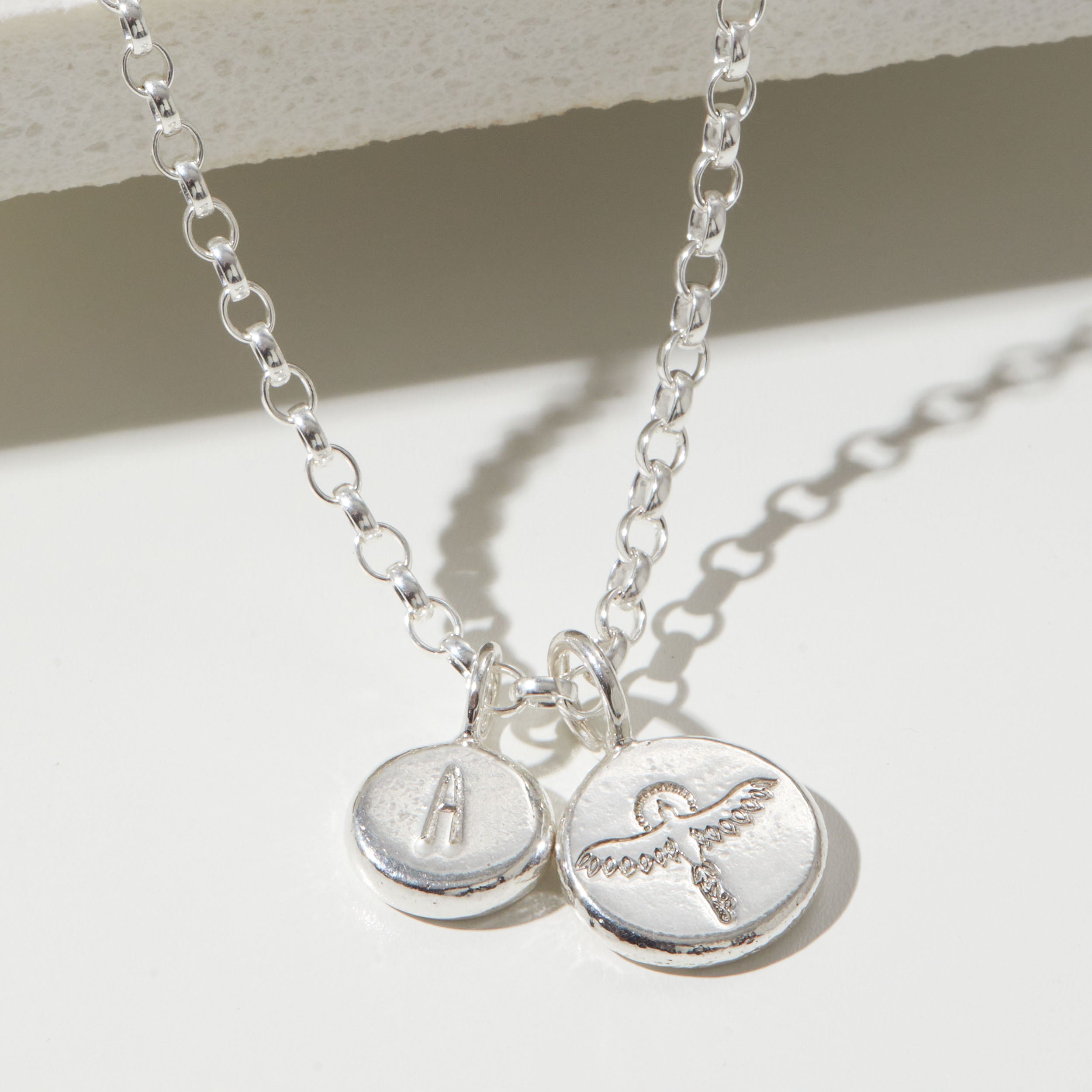Silver necklace with two round pendants on a light background