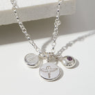 Silver necklace with initial, phoenix and birthstone charms on a white background