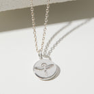 Silver phoenix necklace with a round pendant on a light background