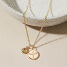 Gold necklace with phoenix and birthstone pendants on a neutral background