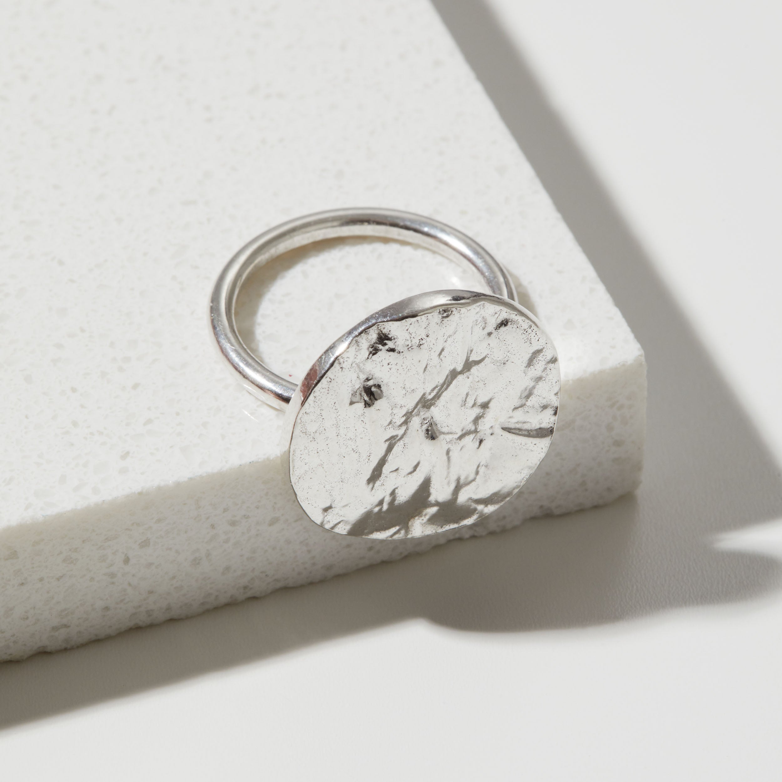 Silver ring with a bark textured circular design on a light background