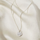 Silver necklace with a bark textured pendant on a soft beige fabric background