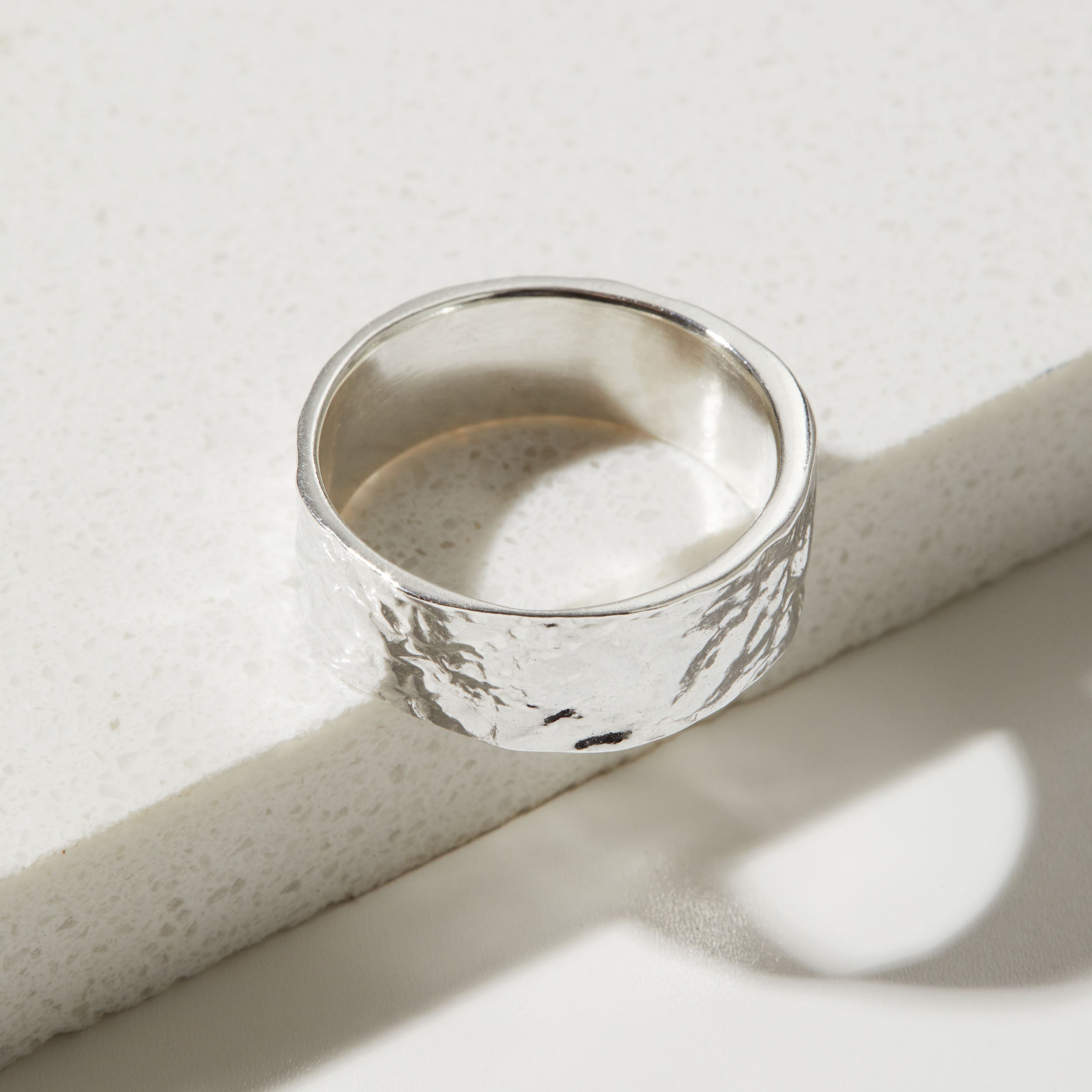 Silver ring with a bark textured surface on a light background