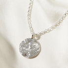 Silver necklace with a statement bark textured pendant on a light background