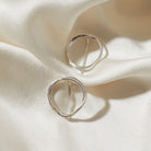 Silver circular earrings on a soft white fabric background