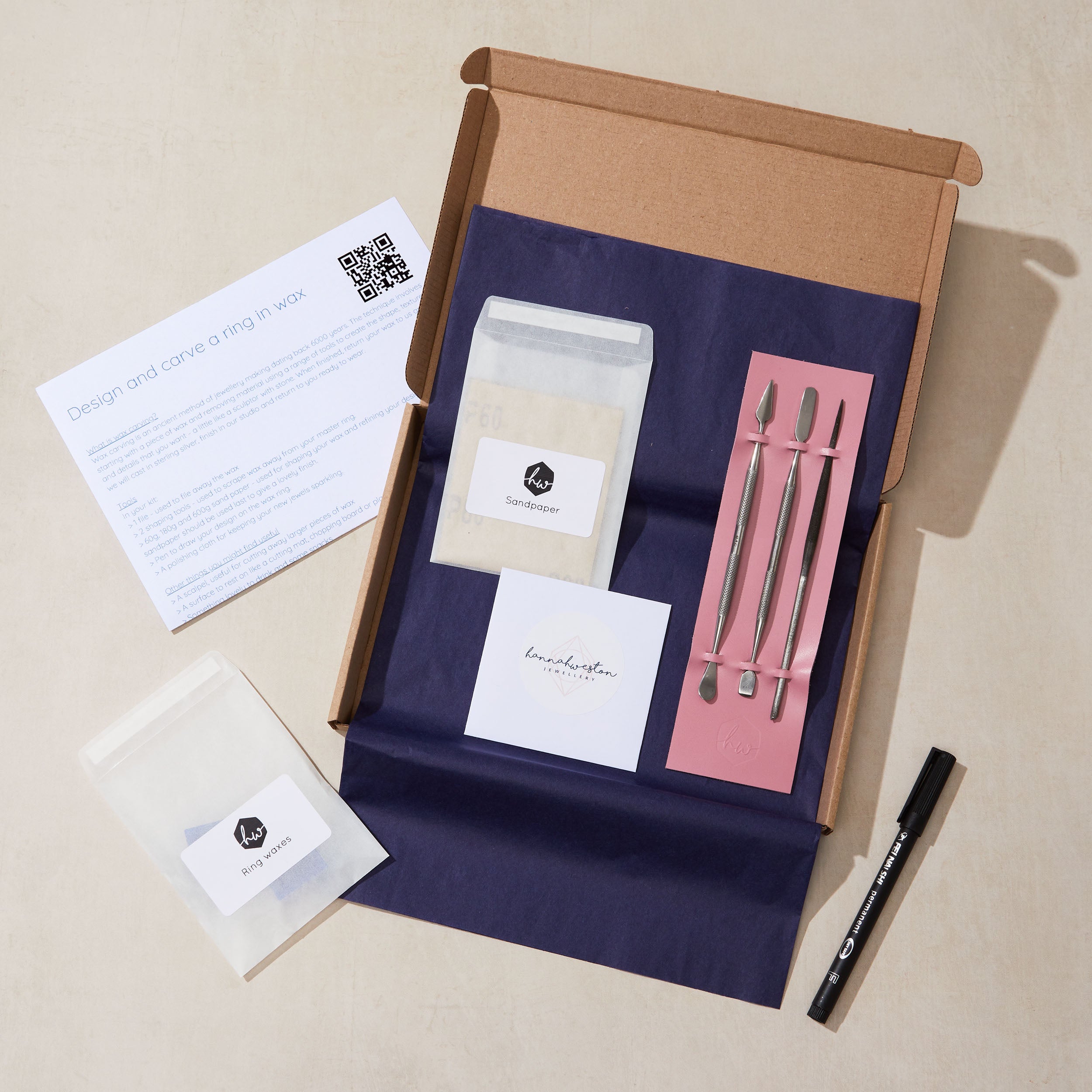 Unboxing of a silver ring carving kit with tools and packaging on a beige background