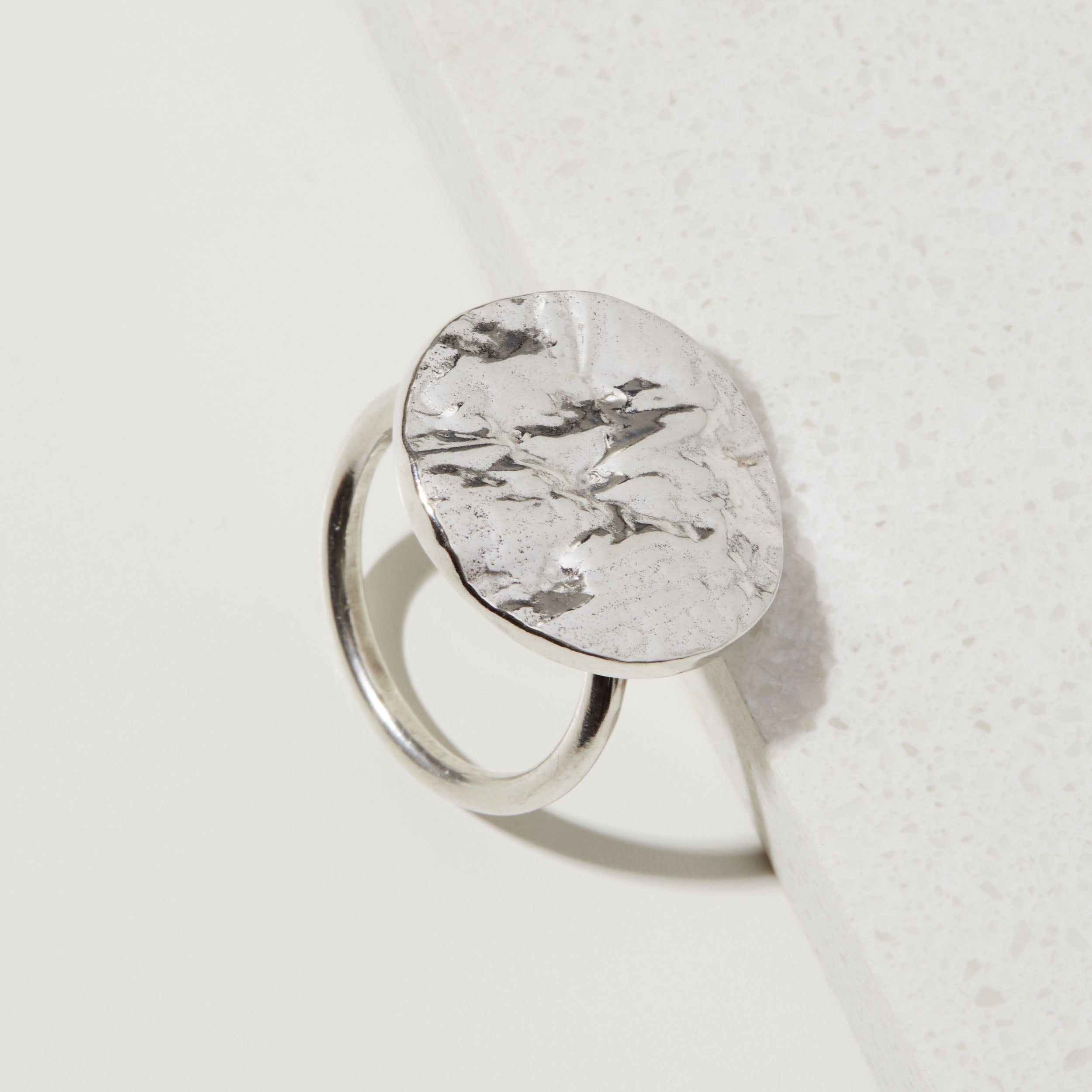 Silver statement tree bark textured ring on a white surface