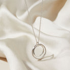 Silver necklace with a double-circle pendant on a white fabric background