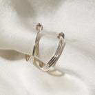 Silver hoop earrings on a white fabric background