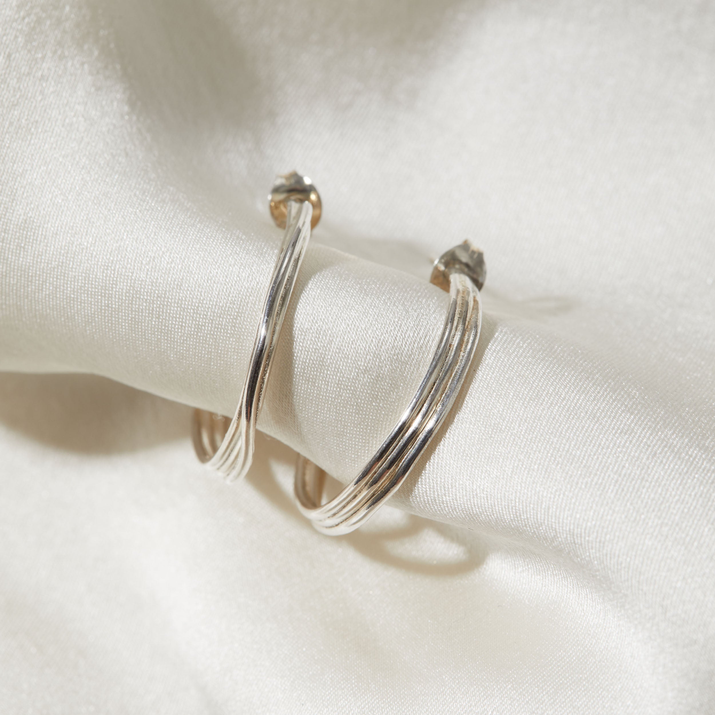 Silver hoop earrings on a white fabric background