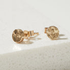 Tiny Gold bark textured stud earrings on a light gray background
