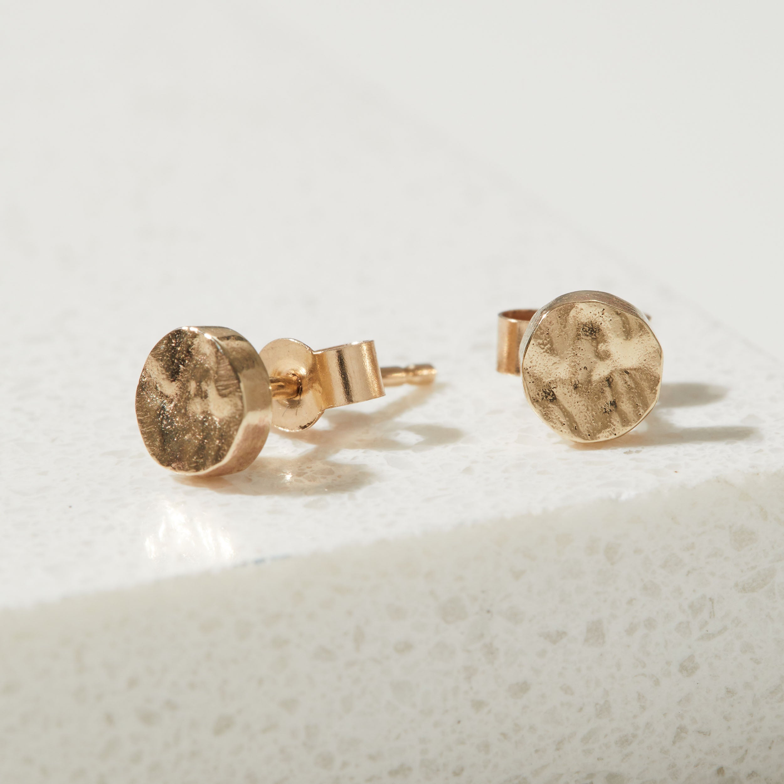Tiny Gold bark textured stud earrings on a light gray background