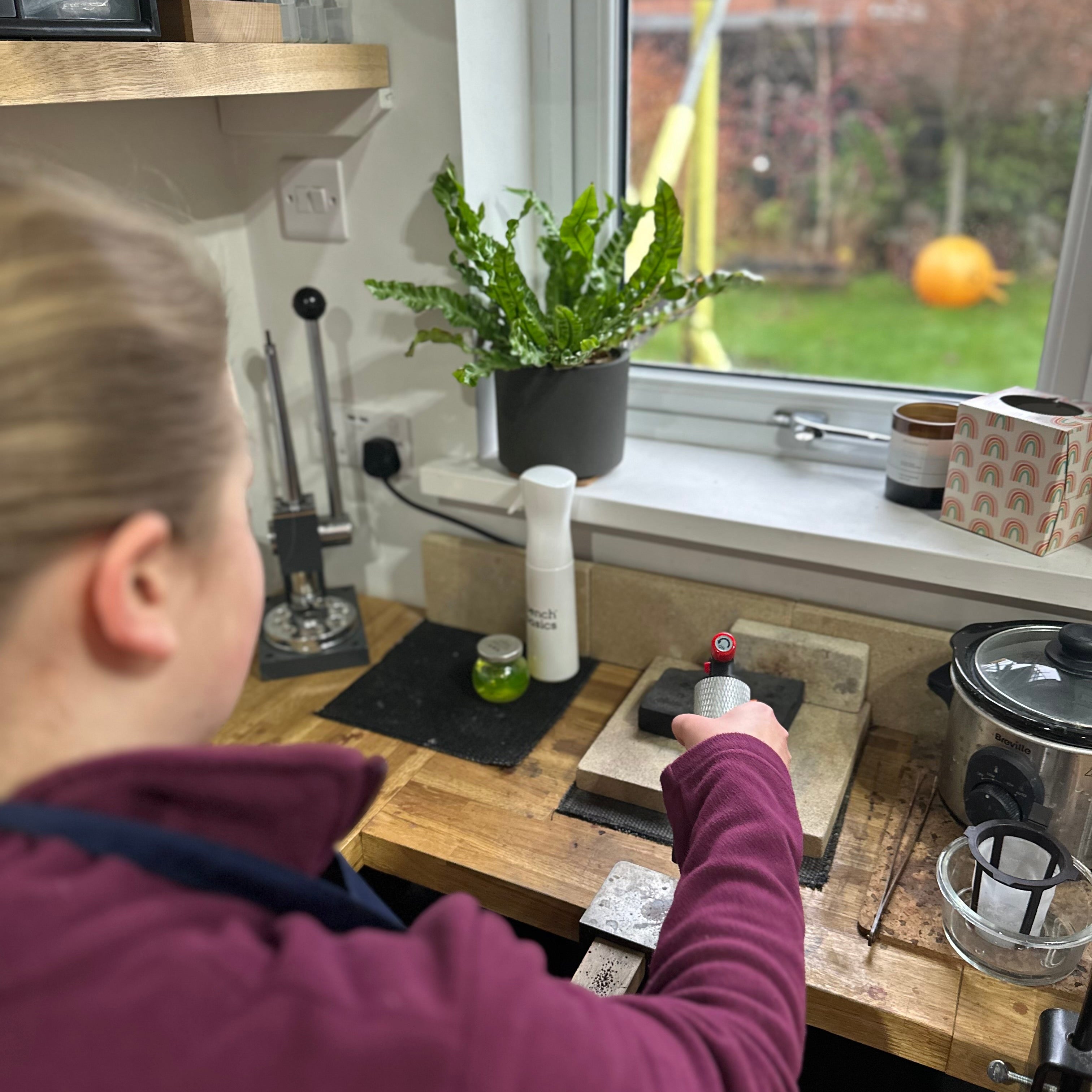 Person making jewellery with a window view of a garden.