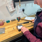 Person working with tools on a wooden workbench in a workshop setting.