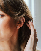 Woman with dark hair showing silver studs in her ears.