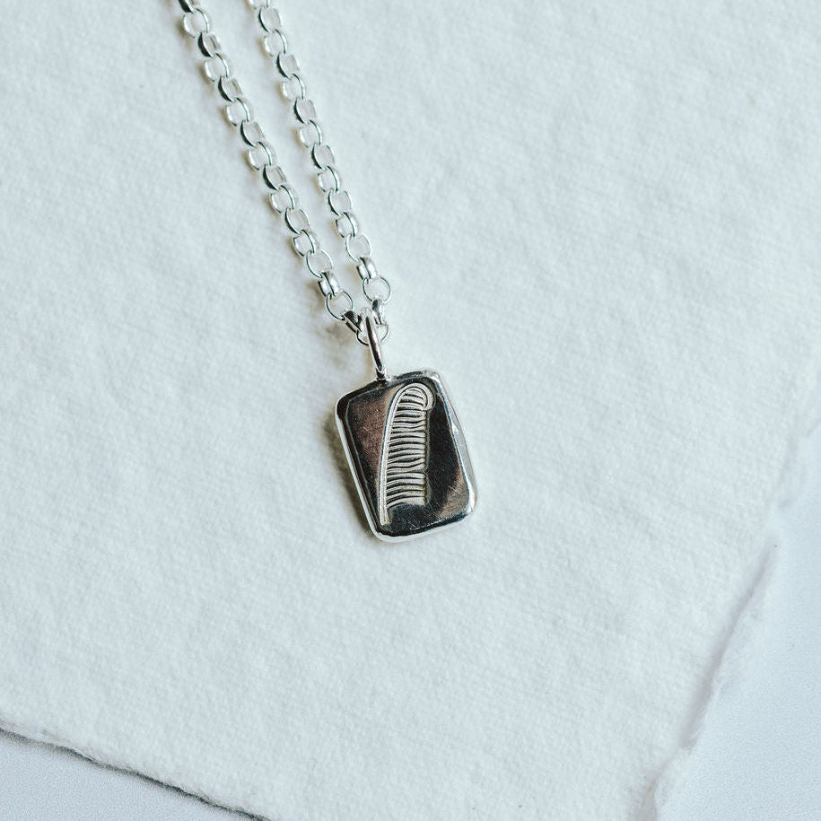 Sterling silver pendant with feather design on a white background