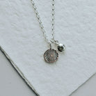 Silver necklace with two pendants on a light gray surface