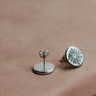 Silver darling heart earrings on a brown surface