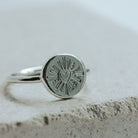 Signet ring with a heart design on a marble tile.