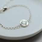 Silver bracelet with a circular heart pendant on a white plate