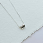 Silver necklace with a small pendant on a light gray background