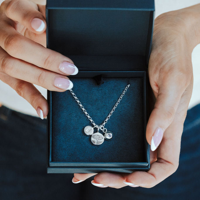 Blue box with pheonix, initial and birthstone pendants on a silver chain.