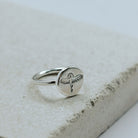 Silver ring with a phoenix design on a textured stone surface