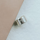 Silver ring with phoenix design on a beige and white background