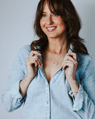 Woman in a denim shirt on a grey background wearing a silver circle necklace