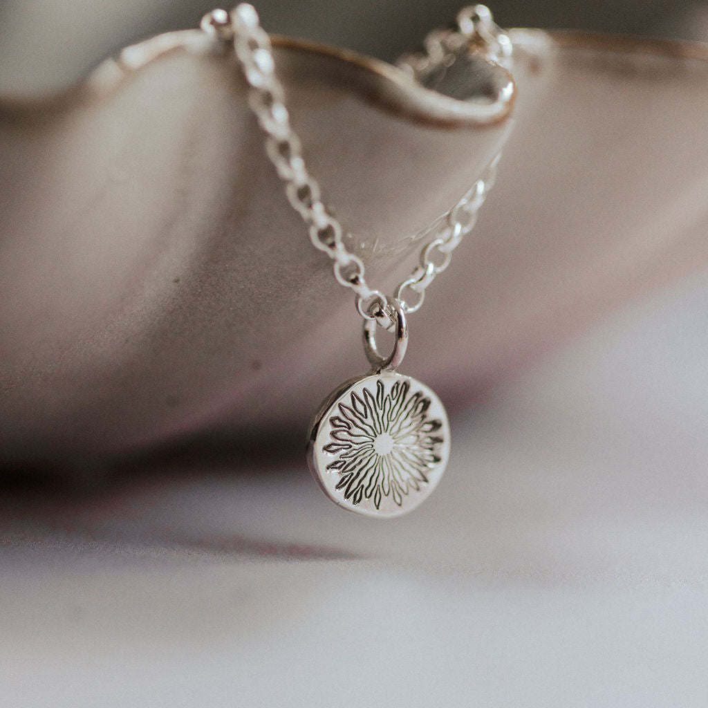 Silver necklace with a sunrise pendant on a soft background